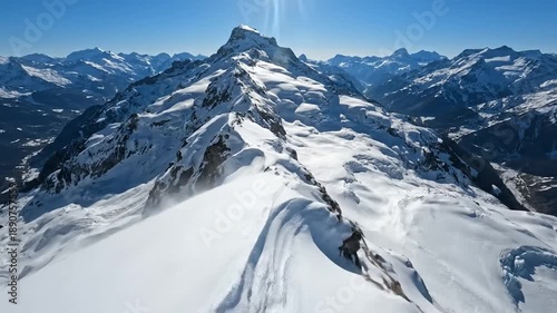 Majestic snow-capped mountains, a rugged peak with wind-blown snow under a clear blue sky