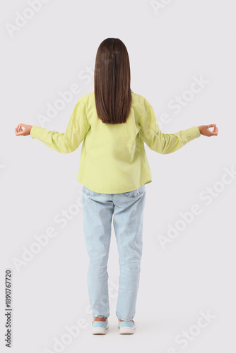 Young woman meditating on white background, back view