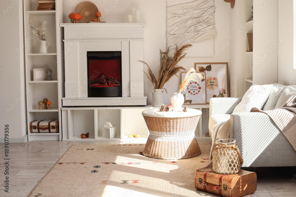 Fototapeta premium Comfortable living room with white fireplace, sofa, coffee table and pumpkins. Autumn concept