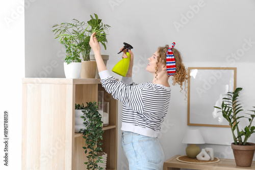 Young woman spraying green ...