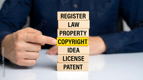 Professional hand pointing at copyright block in a stack of legal words on a desk