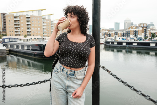 Fotografi Young woman drinking coffee by the docks in london
