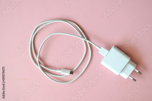 Mobile phone charger, white smartphone charger on pink background. Charger and USB cable type C on pink background