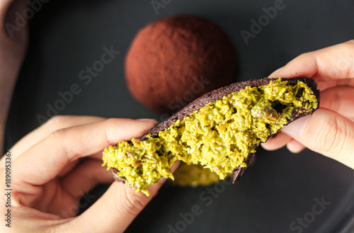 Bilde på lerret A hand stretching a Dubai Chewy Cookie with the chewy outer layer opened to reveal the filling of pistachio and kataifi