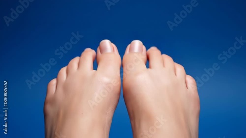A pair of human feet with neatly trimmed toenails on a blue background