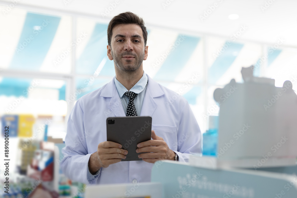 Fototapeta premium Confident pharmacist holding digital tablet while managing medical information. Male healthcare professional using technology to enhance pharmaceutical accuracy and patient care quality.