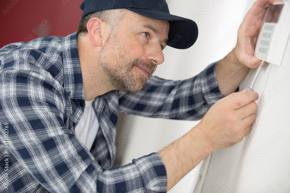 © auremar - hvac technician repairing digital heating and cooling thermostat