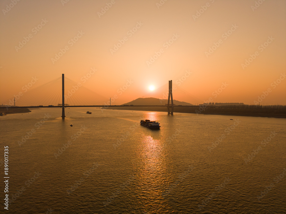 Fototapeta premium River landscape with bridge and cargo ship at sunset in Wuhan China