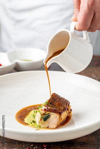 Chef pouring sauce over suprema di pollo during fine dining presentation