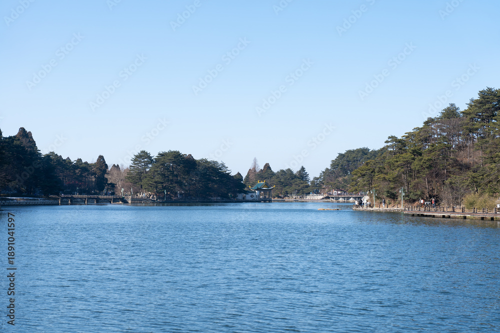 Fototapeta premium A tranquil lake reflects the trees and clear sky in Lushan Mountain, Jiangxi China