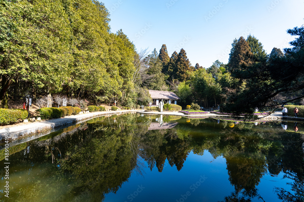 Obraz premium A serene lake reflects trees and a traditional building in Lushan Mountain, Jiangxi China