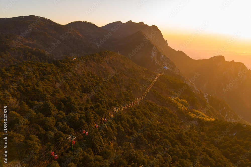 Fototapeta premium Tourists walk along a scenic mountain path in Lushan Mountain, Jiangxi China during sunset