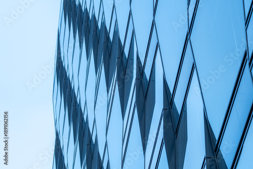 Urban modern architecture building facade of glass with abstract pattern showing reflection into wide sky creating minimal background copyspace for design