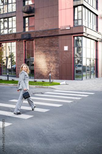 Wallpaper Mural Professional woman broker crossing street at pedestrian walk near office or apartment building real estate expert walking in modern urban district near new construction Torontodigital.ca