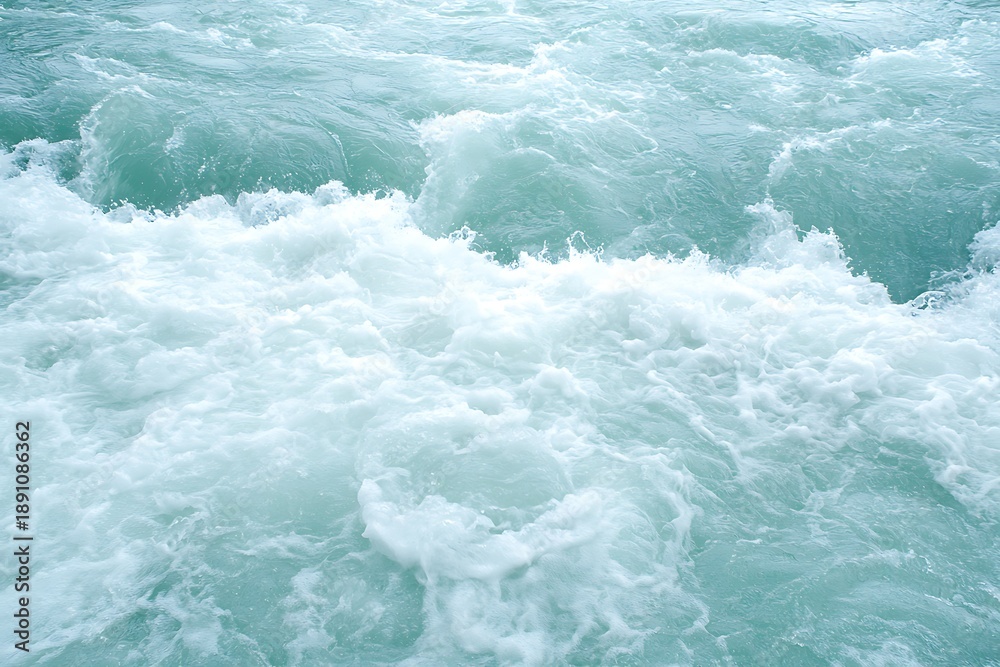 Fototapeta premium Turbulent Ocean Waves Churning with White Foam Against a Calm Aqua Blue Background
