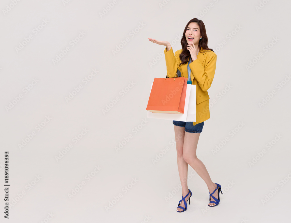 Fototapeta premium Shopping lifestyle woman holding bags Asian woman walking with confident expression representing modern consumer behavior retail trends fashion purchase decisions and positive shopping experience