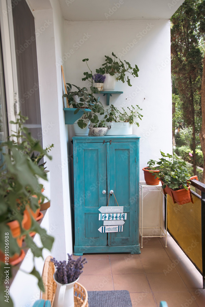 Fototapeta premium Small balcony with blue wooden bench and summer flowers.