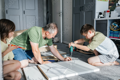 Obraz na plátně Father and sons assembling furniture, teamwork home improvement