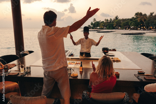 Chef entertaining guests at luxury teppanyaki restaurant during sunset