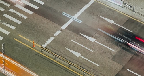 Vehicles traverse an urban street, highlighting the continuous flow of traffic with visible lane markings and blurred motion effects. Time-lapse, Seoul, South Korea