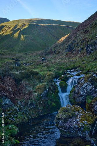 Tranquil Scottish gorge with cascading waterfall.