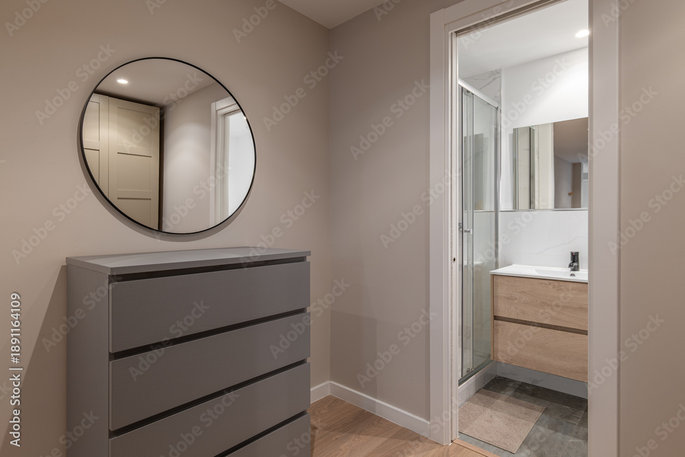 custom made wallpaper toronto digitalA modern bathroom interior featuring a gray dresser and a round mirror. The space is well-lit with a glass shower and wooden vanity.