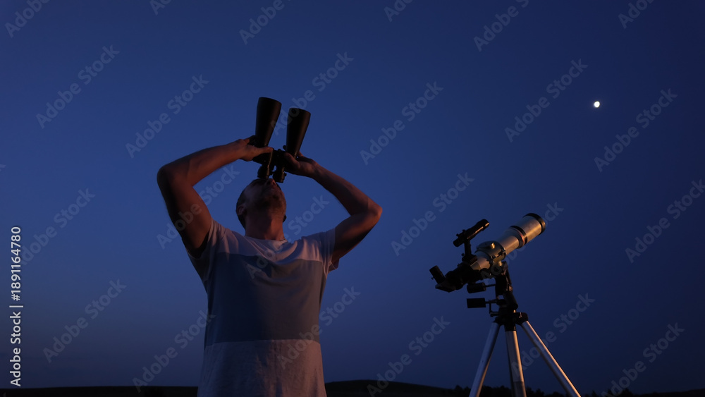 Fototapeta premium Amateur astronomer using telescope and binoculars for watching stars, Moon, planets and other celestial objects from a field in nature.