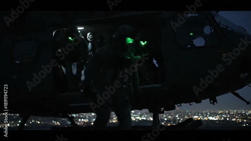 Military personnel entering a helicopter at night with city lights background