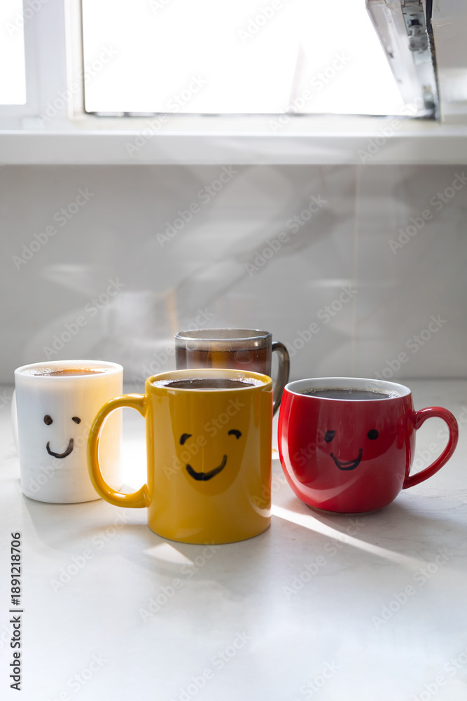 Obraz premium Four mugs of hot coffee sit on a table in a bright room. Steam rises from the mugs as sunlight streams through the window. The scene shows a cozy morning moment.
