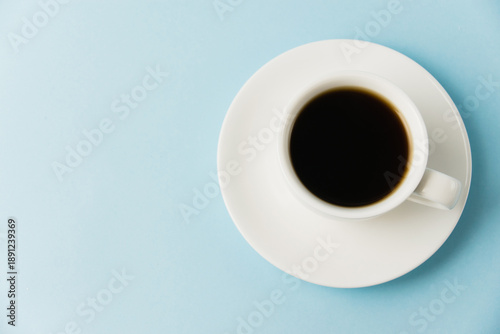 Espresso in a white cup on a blue paper background with copy space. Concept of morning planning for the day