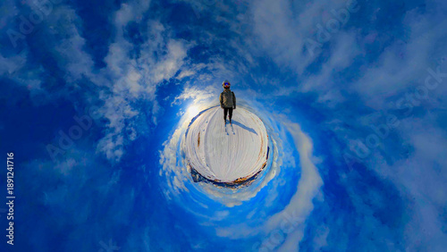 A creative 360-degree projection of a skier standing on the snow-capped peaks of the Seiser Alm in the Dolomites. The spherical panorama is captivating, with a bright blue sky and light clouds.