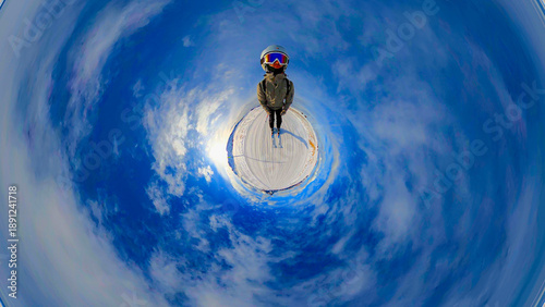 A creative 360-degree projection of a skier standing on the snow-capped peaks of the Seiser Alm in the Dolomites. The spherical panorama is captivating, with a bright blue sky and light clouds.