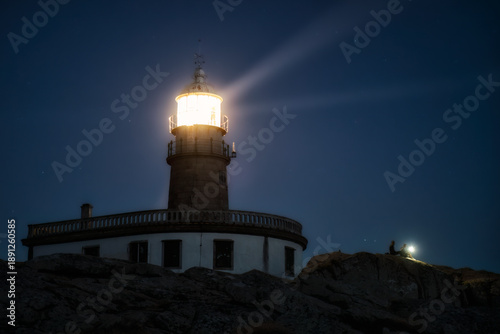Turistas con linterna en el Faro de Corrubedo durante la noche. Galicia, España.
