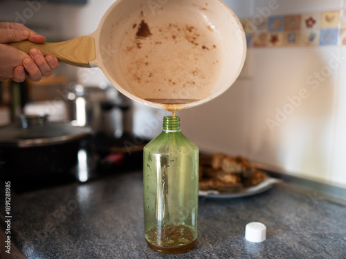 Bild auf Leinwand Pouring used cooking oil from pan into green bottle for home recycling or enviro