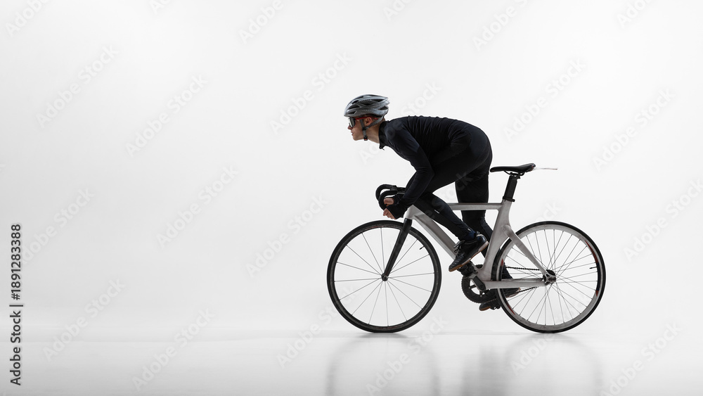 Fototapeta premium Athletic cyclist in aerodynamic position riding road bicycle isolated on white. Concept of speed optimization, racing posture, professional training, competitive sport preparation.