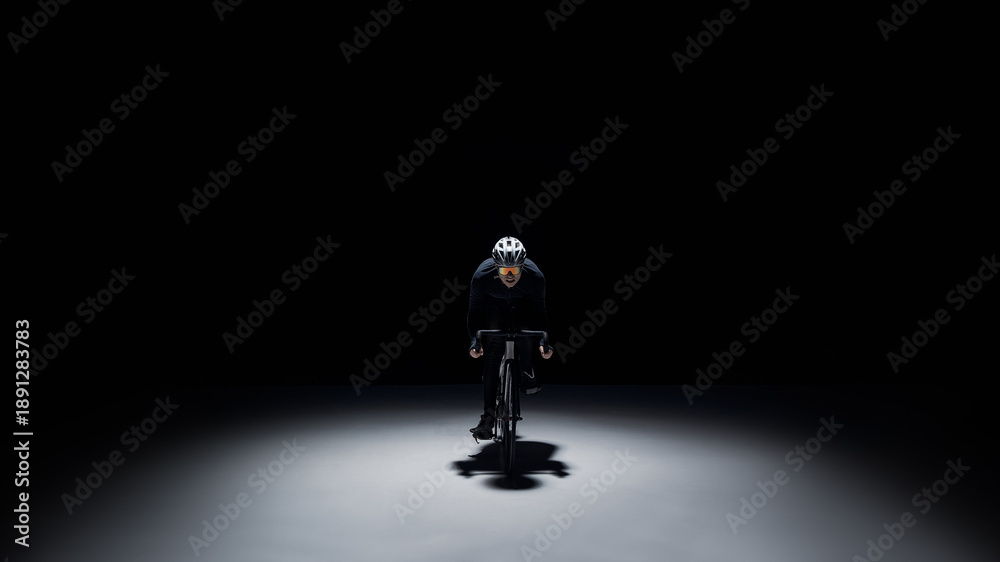 Obraz premium Cyclist riding in spotlight on dark background with copy space. Concept of premium sports advertising, dramatic banner, performance branding, minimal mockup and high contrast campaign design.