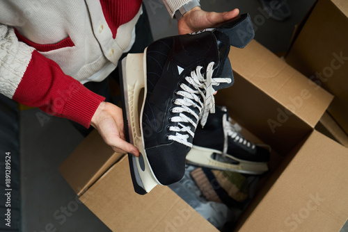 Fotografie Caucasian young adult man holding pair of black ice hockey skates above open car