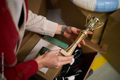 фотографія Caucasian middle aged woman holding trophy with both hands while unpacking cardb