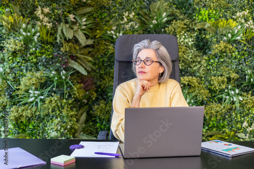 Mature businesswoman thinking while working on a laptop