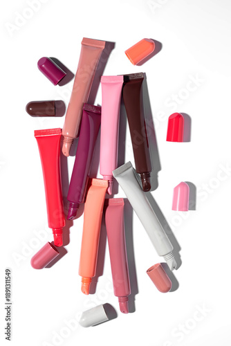 Картината върху платно A collection of beauty products featuring multiple plastic squeeze tubes of lip gloss or lip balm in different pink, red, and brown colors