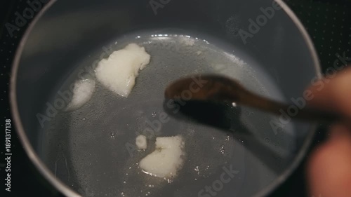 Melting Coconut Oil In Pan, Wooden Spoon Nudging White Solid Into Glossy Liquid, Gentle Sizzle And Clear Heat, Vegan Friendly