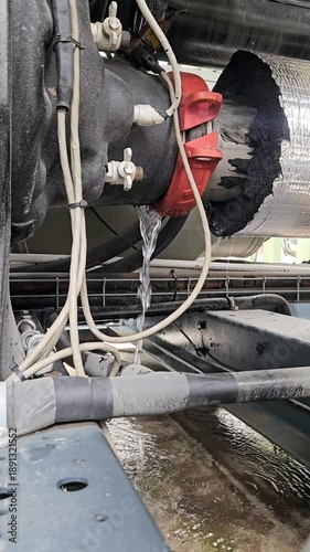 Close-up of a leaking industrial pipe with damaged insulation and wiring.