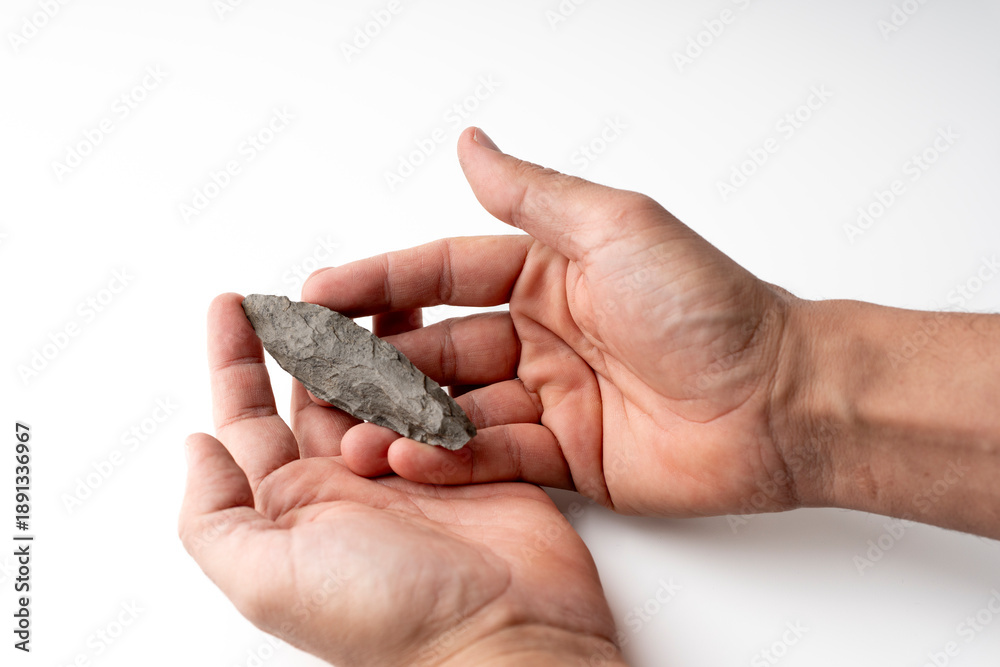 Obraz premium Pov camera. Ancient Paleolithic Flint Spear | Prehistoric Biface Tool from Algerian Sahara. my hand. white bakcround