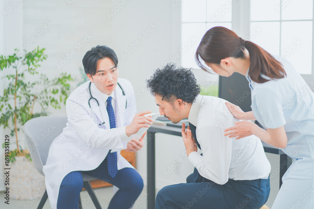 Obraz premium 明るく清潔感のあるクリニックで診察をする若い男性医師と女性看護師