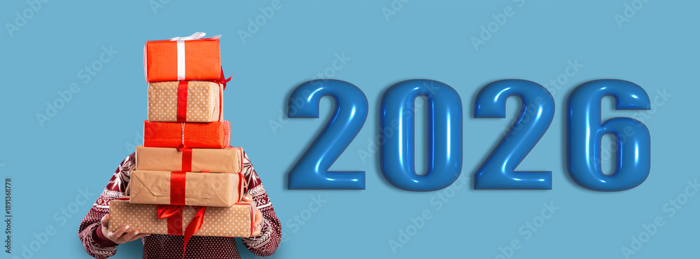 Obraz premium A person holds a stack of colorful gifts next to the large numbers representing the year 2026. This scene captures the spirit of celebration and togetherness.