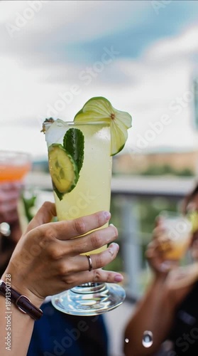 Group of friends clinking diverse colorful cocktails at a rooftop party