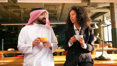 Φωτογραφία Smiling woman talking with colleague authentic muslim man in keffiyeh drinking c