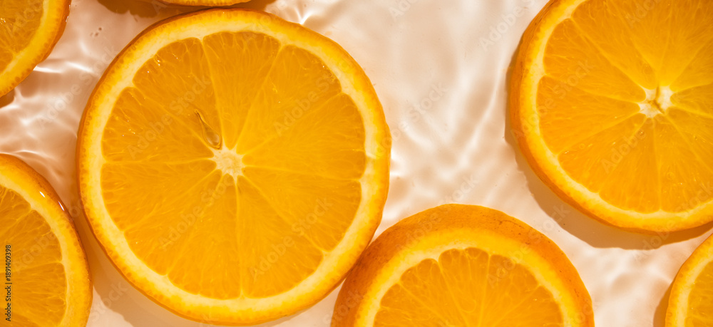Fototapeta premium Top view of orange slices in splashing water.