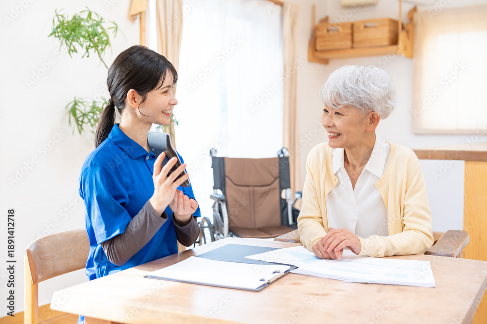 Fototapeta premium シニアに電卓を見せる女性