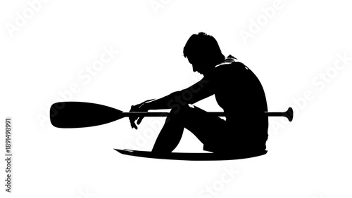 Silhouette of a man sitting on a paddleboard holding a paddle.